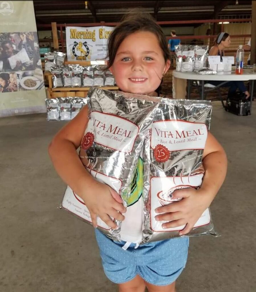 A child holding bags of Vitameal at a Morning Glory Ranch event